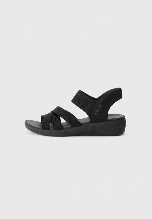 Zwarte sandalen met een sleehak en kruisbanden van mesh stof. Zacht voetbed en rubberen zool verhogen comfort en ondersteuning.
