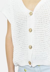 Cardigan bianco lavorato a maglia con maniche corte, caratterizzato da una scollatura a V e cinque bottoni dorati sulla parte anteriore. Tessuto leggero e testurizzato.