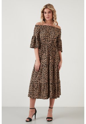 Vestido de leopardo sin mangas con cortos volantes, cinturilla elástica y diseño de falda en capas. Combinado con tacones negros.