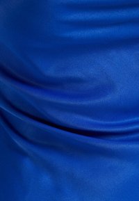 Smooth royal blue fabric with soft folds and subtle texture, illuminated to highlight its silky sheen and fluid draping.