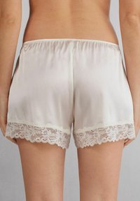 Witte satijnen shorts met een gladde textuur, met een delicate kantafwerking aan de zoom en een elastische tailleband voor comfort.