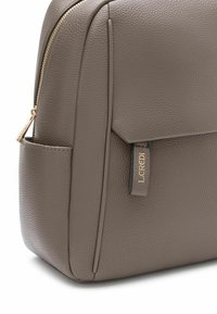Borsa in finta pelle marrone con una texture, cerniera dorata e un piccolo etichetta con logo. Presenta una forma strutturata e dettagli di tasche laterali.