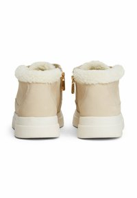 Bottines en daim beige avec un col en fausse fourrure blanche, des zips dorés et une épaisse semelle en caoutchouc blanc. Texture douce avec une finition lisse.