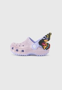 Lila glittriga träskor med ventilationshål, ett mjukt lila rem och en flerfärgad fjärilsdekoration bak.