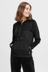 Hoodie noir zippé en tissu doux et pelucheux. Comprend une capuche, des poches avant et des détails en métal argenté. Assorti à un pantalon noir.