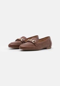 Mocassins en cuir marron avec une semelle plate, ornés d'une chaîne dorée sur le devant. Texture lisse et design à bout rond.