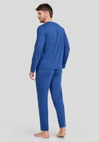 Camisa de pijama de manga larga azul y pantalones a juego, hechos de un tejido suave con una textura lisa. Diseñados con un ajuste holgado.