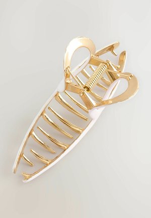 Goldfarbiger Haarklammer aus Metall mit einer weißen Kunststoffbasis, ausgestattet mit einem Federmechanismus und einem länglichen, geschlitzten Design mit gebogenen Enden.
