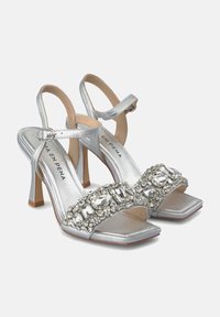 Sandalias de tacón con tiras en plata y punta cuadrada, adornadas con brillantes rhinestones en la tira delantera y un tacón de aguja.