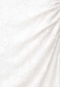 Tessuto bianco con un motivo floreale testurizzato, dettagli in rilievo, superficie liscia e drappeggio elegante.