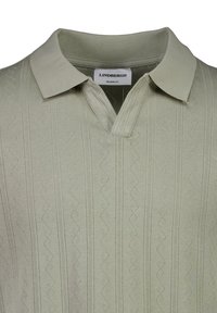 Polo shirt verde chiaro con un motivo a zigzag testurizzato, una vestibilità comoda e colletto. Apertura a V ben visibile e un sottile design a maglia.