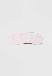Gumeni sloj tenisice, pretežno svijetlo ružičaste boje s teksturiranim uzorkom. Sadrži Nike logo i kružne dizajnerske elemente na potplatu.