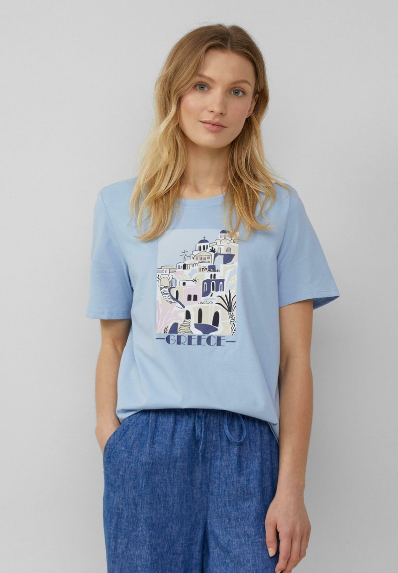 T-shirt en coton bleu clair avec une impression graphique d'architecture grecque et le mot "Grèce". Manches courtes et col rond.