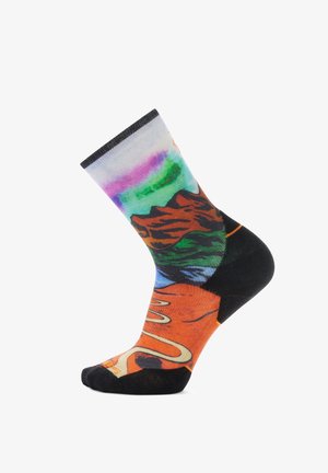 Calcetines coloridos con un diseño vibrante de un paisaje montañoso en tonos de naranja, verde y púrpura. La puntera y el talón son negros.