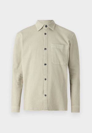 Košeľa s dlhým rukávom a gombíkmi z ľahkého béžového materiálu. Má špicatý golier, vrecko na hrudi a čierne gombíky. Jednoduchý, textúrovaný dizajn.