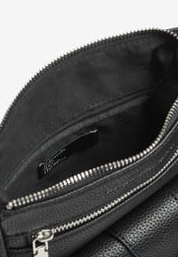 Borsa in pelle nera con texture, con cerniera argentata, aperta per mostrare l'interno in tessuto nero e una piccola tasca con zip all'interno.