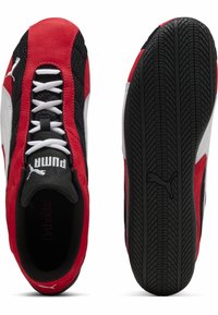 Zapatillas deportivas rojas y negras con materiales de malla y ante. Presentan un logo blanco, texturas contrastantes y una suela de goma con un diseño de relieve.