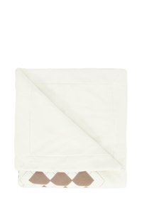 Deken in crème stof, met een diamanten patroon in bruin en beige aan één kant; gladde textuur met een gevouwen hoek.
