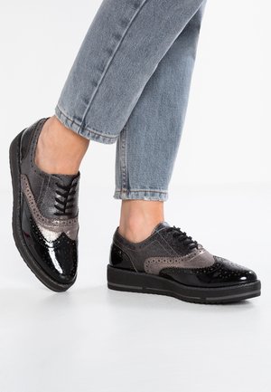 Zapatos brogue en negro y gris con un acabado brillante de charol, tejido gris texturizado, acentos perforados y una suela gruesa estilo zapatilla.
