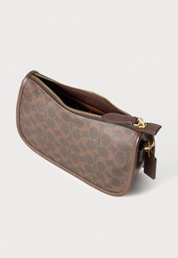 Brown leather bag with a circular pattern, zip closure, and gold hardware accents. Soft texture, curved shape, and a hanging tag detail.