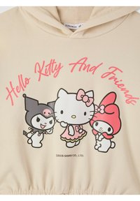 Felpa beige con un design stampato che raffigura tre personaggi dei cartoni animati: Hello Kitty, My Melody e Kuromi, con accenti colorati e testo.