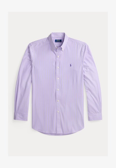 Camisa de manga larga abotonada en morado claro con rayas verticales blancas, que presenta un cuello clásico y un pequeño logo bordado en el pecho.
