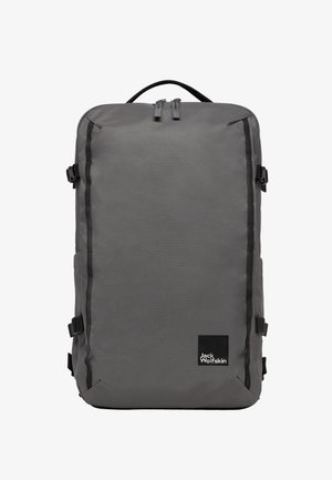 Sac à dos en tissu gris de forme rectangulaire, avec des bretelles noires, des zips et un logo en bas à droite.