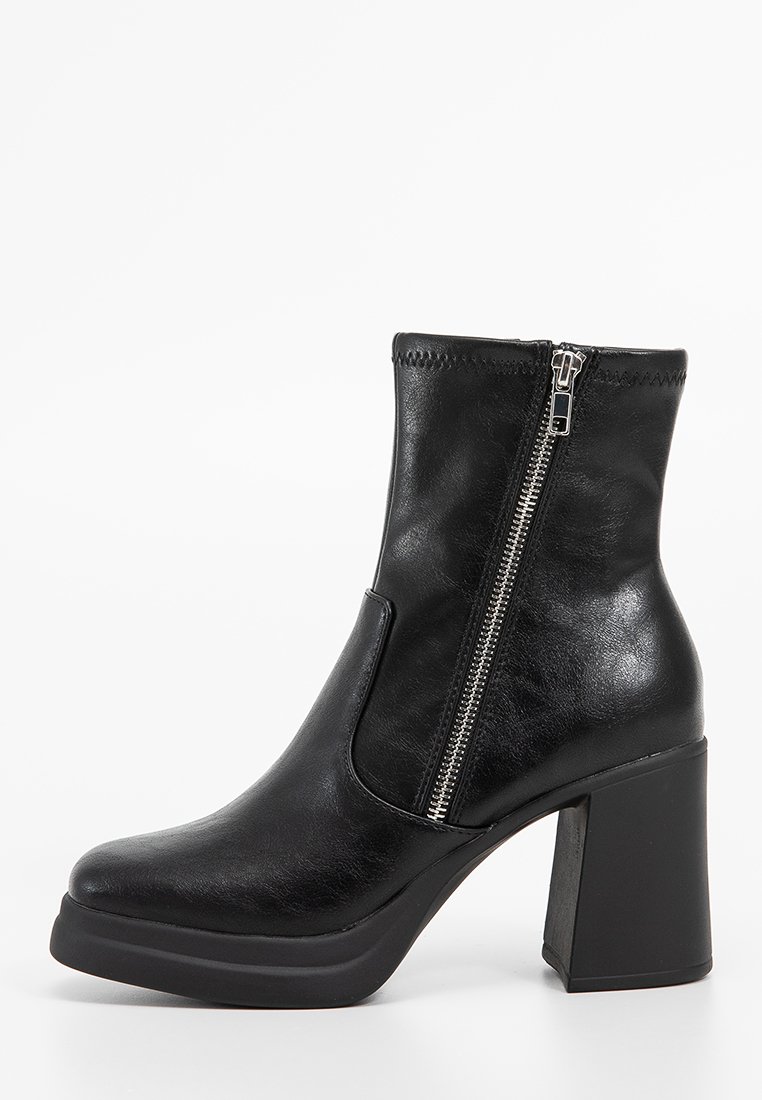 Bottines noires en cuir lisse, dotées d'un talon bloc, d'une fermeture éclair latérale et d'un bout arrondi. Les coutures sont discrètes le long du bord supérieur.