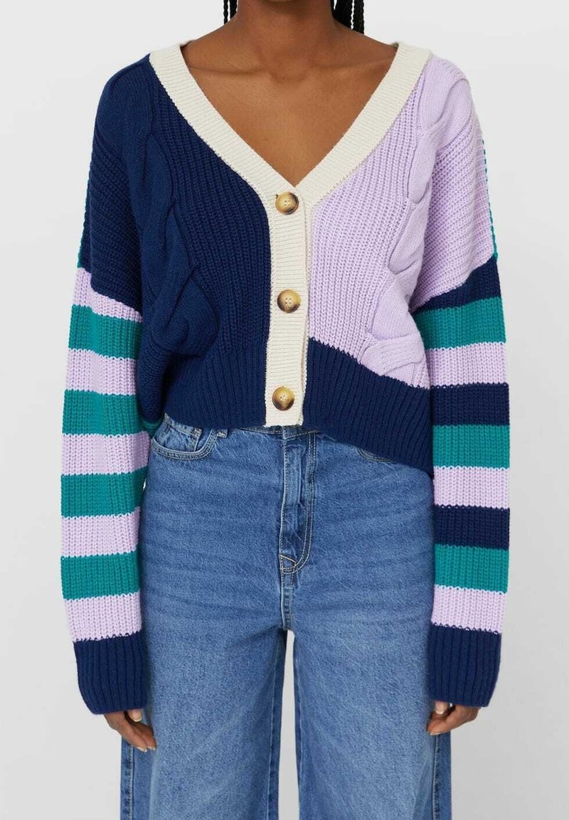 Gebreide cardigan in marineblauw, lila en groen met een V-hals en twee grote knopen. Heeft kabelpatronen en gedurfde gestreepte mouwen.