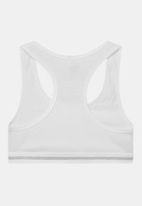 Soutien-gorge de sport blanc avec une texture côtelée, un design à dos nageur et une bande argentée le long du bas.