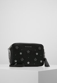Borsa a tracolla in pelle nera con decorazioni a forma di stella, borchie argentate e tracolla a catena. Include un tassel decorativo su un lato.