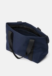 Navyfarbene Stofftasche mit schwarzen Griffen, geräumigem Innenraum und einem Reißverschlussfach. Sie zeichnet sich durch eine strukturierte Form und eine langlebige Textur aus.