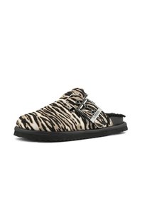 Sandale à glissière doublée en fourrure, avec un motif rayé zèbre noir et beige, un détail de boucle et une semelle en caoutchouc noir texturé.
