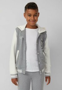 Veste varsity grise et blanche avec capuche, dotée d'un patch sur le devant, de boutons-pression, de manchons rayés contrastants et d'une coupe décontractée.