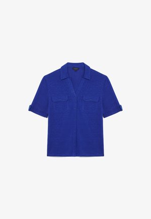 Korte mouwen, blauwe overhemden met knopen gemaakt van zachte stof, voorzien van een kraag en twee borstzakken met klepjes. Opgerolde mouwuiteinden.