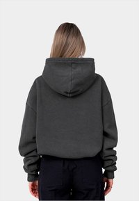Sweat à capuche gris foncé, fabriqué en tissu texturé, avec une coupe décontractée, des épaules tombantes et des poignets côtelés. Conçu avec une capuche spacieuse.
