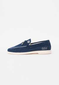 Donkerblauwe loafers van dennenstof met witte accenten. Heeft een ronde neus, instapontwerp en branding aan de buitenkant.