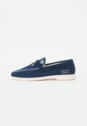 Dunkelblaue Loafers aus Denimstoff mit weißen Akzenten. Verfügt über eine abgerundete Zehenpartie, ein Schlupfdesign und eine Markenkennzeichnung an der Außenseite.