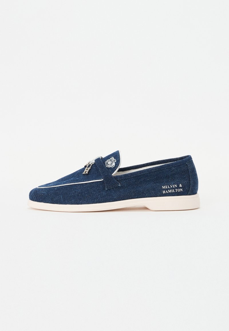 Donkerblauwe loafers van dennenstof met witte accenten. Heeft een ronde neus, instapontwerp en branding aan de buitenkant.