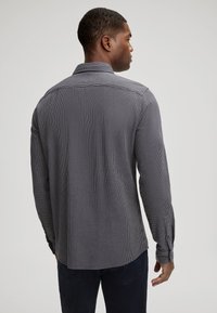 Heren overhemd met lange mouwen in een donkergrijs en wit ruitpatroon, met een button-down kraag en manchetten, een rechte zoom en een zachte textuur.