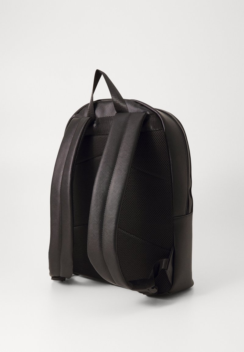 Černý batoh s strukturovanou tkaninou, polstrovanými popruhy a horním držadlem. Má elegantní design a zakřivený tvar pro ergonomické nošení.