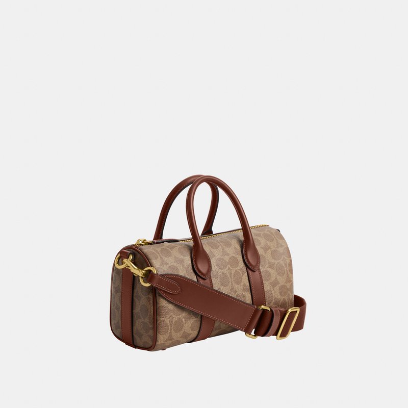 Bolso pequeño cilíndrico beige con patrón distintivo, asas de cuero marrón, correa de hombro ajustable y detalles metálicos en tono dorado.