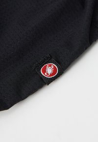 Crna tkanina s teksturiranim uzorkom, s crvenim i bijelim logom u donjem kutu, prišivenim na materijal.
