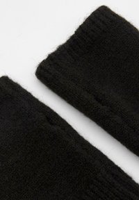 Mustaa neulottua sormettomaa hanskaa, joissa on pehmeä tekstuuri, ribbireunat ja sileä pinta, suunniteltu lämmölle ja joustavuudelle.