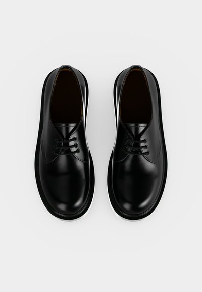 Paire de chaussures à lacets en cuir noir poli vues de dessus sur un fond blanc uni.