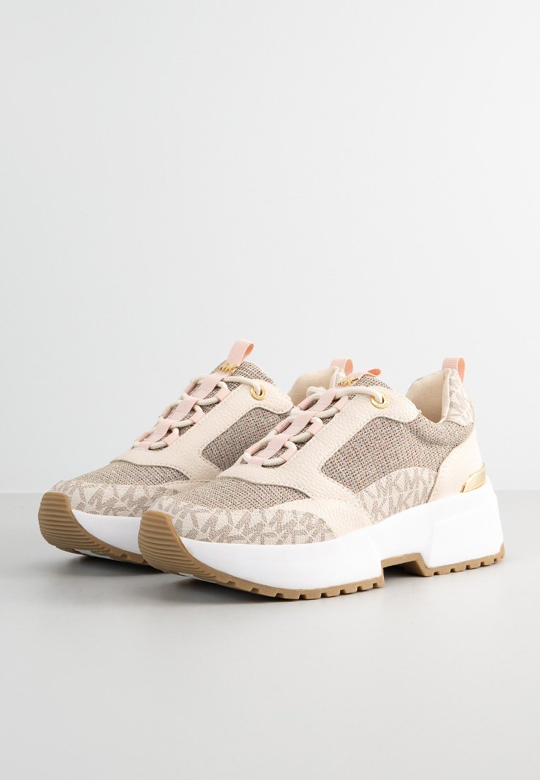 Beige und hellrosa Plateausneaker aus strukturiertem Stoff, mit gemusterten Details, weißen dicken Sohlen und goldenen Akzenten auf einer weißen Fläche.