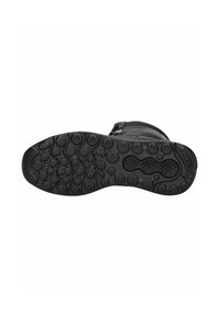 Suela de zapato de goma negra con texturas variadas, que incluyen patrones circulares elevados y ranuras para mayor agarre, con una puntera redondeada y bordes curvados.