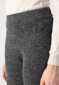 Sive pletene tajice s visokim, elastičnim pojasom, koje se odlikuju mekim, teksturiranim materijalom koji je gladak i topao.
