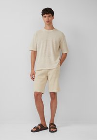 Lichtbeige gebreide top en shorts set, met een gestructureerd patroon, een ontspannen pasvorm, en gecombineerd met bruin gespsandalen.