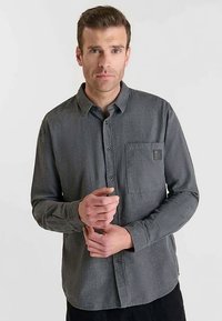 Grijs overhemd met knopen, een borstzak en een label. Gemaakt van een textuurstof, met een klassieke kraag en lange mouwen.